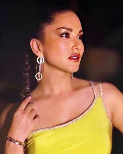 Sunny Leone graces a red carpet event in a radiant yellow dress and dazzling ear ornaments.